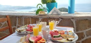 a table with two plates of food and glasses of orange juice at Amphora Guesthouse in Himare