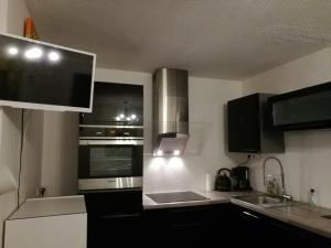 una cocina con electrodomésticos de acero inoxidable y armarios negros en FLOREVA Proche plage et thalasso, en Concarneau