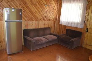 sala de estar con sofá y nevera en Cabañas y Tinajas Borde río, en Licán Ray