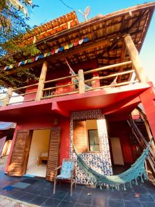 una casa rossa con una sedia blu davanti di Mandacaru Chalés e Suítes Itamambuca a Ubatuba
