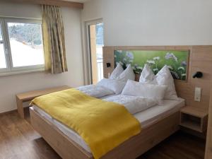 a bedroom with a bed with a yellow blanket on it at Appartements Blumenwiese in Ramsau am Dachstein