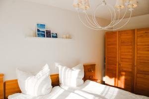 Un dormitorio con una cama con sábanas blancas y una lámpara de araña. en Ferienwohnung Bergoase, en Fischen