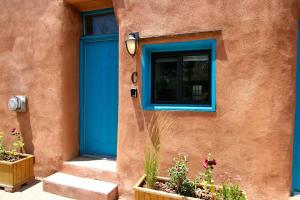 een blauwe deur aan de zijkant van een gebouw met bloemen bij Closson Getaway - Courtyard - Railyard and Plaza in Santa Fe