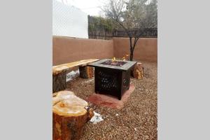 een vuurplaats in een tuin met een houten bank bij Closson Casita - Patio & Fire Pit - Near Plaza - 1BR in Santa Fe