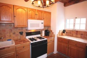 een keuken met een zwarte kachel en een magnetron bij Closson Casita - Patio & Fire Pit - Near Plaza - 1BR in Santa Fe