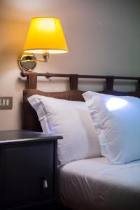 a bed with a yellow lamp and white pillows at Bastimento in Fiorenzuola dʼArda