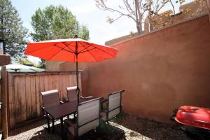 a table with a red umbrella next to a fence at Galisteo Getaway - Courtyard - Near Railyard in Santa Fe