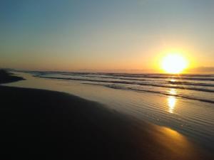 un tramonto su una spiaggia con l'oceano di Suíte Boqueirão Tati Ortega a Ilha Comprida