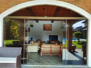 uma porta de pátio aberta com uma sala de estar numa casa em Casa com piscina em condomínio fechado no Guarujá em São Paulo
