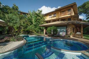 a house with a swimming pool in front of a house at Hotel Via dos Corais in Praia do Forte