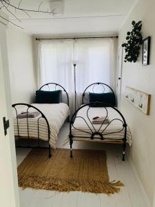 two beds in a room with a window at Cooper's Cottage in Nelson