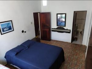 a bedroom with a blue bed and a bathroom at Guest House Vento e Mar in Arraial do Cabo