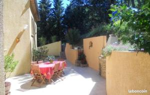 un patio con mesa, sillas y una valla en Chez Mamie Riclaude, en Orsan