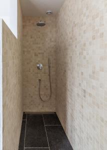 ein Bad mit einer Dusche in einer gefliesten Wand in der Unterkunft vakantiewoning le jardin de grand-mére in Oudenburg