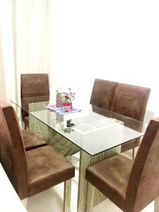 Quarto - Condomínio في ماكابا: طاولة زجاجية مع كراسي بنية وطاولة زجاجية مع طاولة خارجية