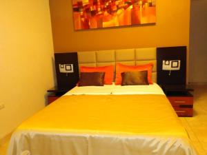伊卡的住宿－伊卡格蘭酒店，一间卧室配有带橙色枕头的大型黄色床