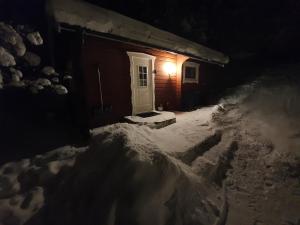 a house with a white door in the snow at night at Backamgården in Sälen