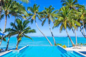 una piscina sulla spiaggia con palme e l'oceano di Little Polynesian Resort a Rarotonga