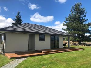 a small house with a deck in a yard at Twizel - Apartment on Woodley in Twizel