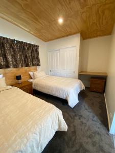 a bedroom with two beds and a wooden ceiling at Country Retreats on Ranzau 2 in Nelson