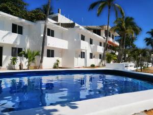 a large swimming pool in front of a white house at Hotel Villa Mexicana Puerto Escondido in Puerto Escondido