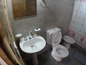 y baño con lavabo, aseo y espejo. en Cabañas del Lagarto en Colón