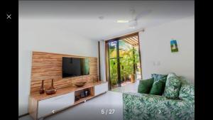 a living room with a couch and a flat screen tv at Bangalô duplex à beira-mar in Camaçari