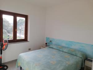 sypialnia z niebieskim łóżkiem i oknem w obiekcie Residence Li Menduli w mieście San Teodoro