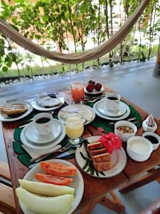 une table avec des assiettes de nourriture et des tasses de café dans l'établissement Pousada NÔ Caraíva, à Caraíva