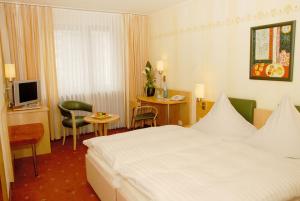 オッフェンバッハにあるホテル グラフの白いベッドとテレビが備わるホテルルームです。