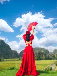 kobieta w czerwonej sukience trzymająca czerwony parasol w obiekcie Hang Mua Central Homestay w mieście Ninh Binh