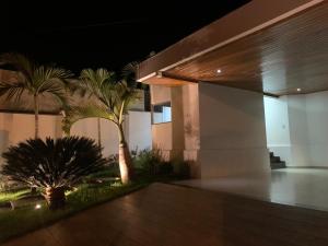 a building with palm trees in front of it at night at Casa Recanto da Paz in São João Batista do Glória