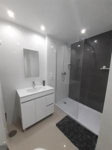 a white bathroom with a shower and a sink at Apto T1 Sweet Home in Praia