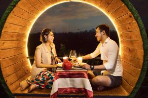 a man and a woman sitting at a table in a round room at S'Bungalow Bến Tre in Ben Tre