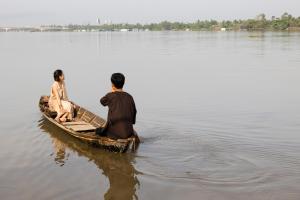 two people sitting on a boat in the water at S'Bungalow Bến Tre in Ben Tre