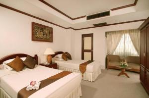 a hotel room with two beds and a chair at Chiangmai Ratanakosin Hotel in Chiang Mai
