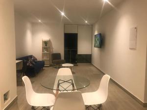 ein Wohnzimmer mit einem Glastisch und weißen Stühlen in der Unterkunft Vive - Descansa - Disfruta in San Bartolo