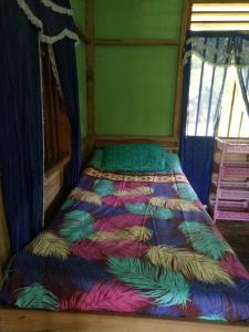 a bed with a colorful comforter in a room at Green Lodge Tangkahan in Tangkahan