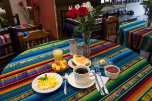 einen Tisch mit Frühstückslebensmitteln und eine Vase Rosen in der Unterkunft Hostal Alcala in Quito