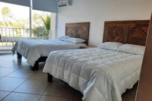 two beds in a bedroom with a view of a balcony at Departamento 105 , paraiso del pacifico in Coyuca