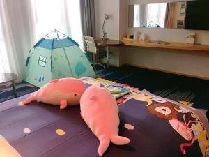 a bedroom with a bed with a stuffed pig on the floor at Holiday Inn Express - Qingdao West Coast, an IHG Hotel in Huangdao