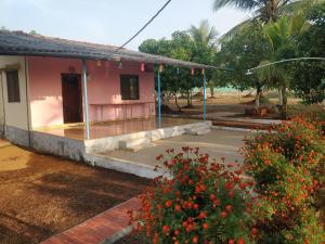 une maison avec une terrasse couverte et des fleurs devant elle dans l'établissement Shree Samarth Farmhouse, à Murud