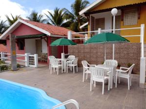 un patio con mesas y sombrillas junto a una piscina en Villa Manary, en Itamaracá
