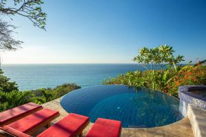 a swimming pool with two chairs and the ocean at Anamaya Resort in Montezuma