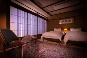 een kamer met 2 bedden en stoelen en een raam bij Kyotoya in Takeo