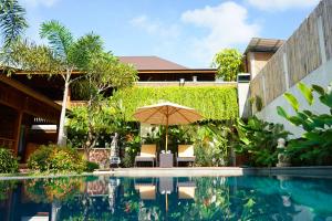 un patio con sombrilla y piscina en La'villaris hotel & resto, en Kuta Lombok