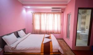Habitación de color rosa con cama y espejo en OYO 789 Hotel Shivam Plaza en Katmandú