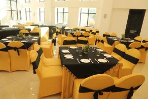 a banquet hall with tables and yellow chairs at City Choice Inn in Kulu