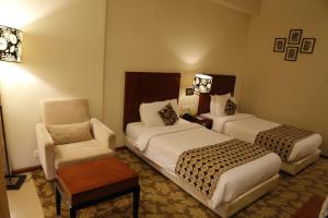 una habitación de hotel con 2 camas y una silla en The Aures (formerly known as Keys Select The Aures), en Aurangabad