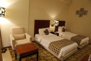 una habitación de hotel con 2 camas y una silla en The Aures (formerly known as Keys Select The Aures), en Aurangabad